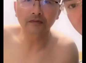 A seductive older Chinese gentleman upon a tailored suit, teasing with confident allure.
